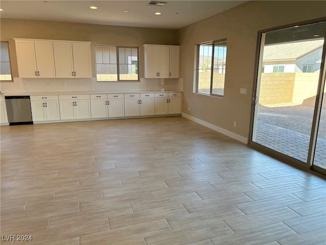 kitchen with stainless steel dishwasher, plenty of natural light, and white cabinetry