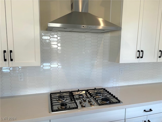 kitchen featuring white cabinets, tasteful backsplash, stainless steel gas stovetop, and wall chimney exhaust hood