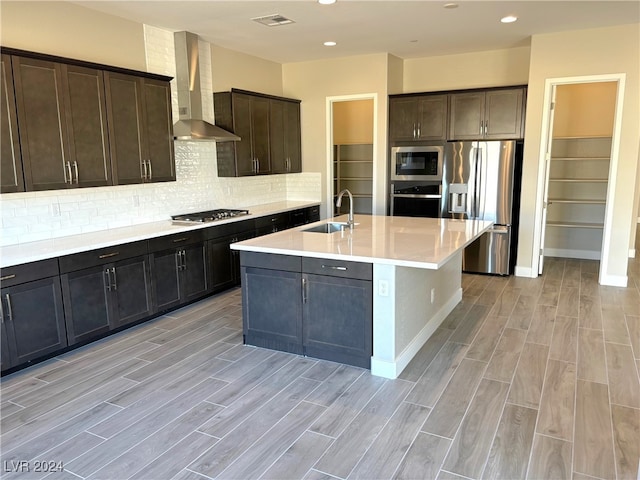 kitchen with sink, light hardwood / wood-style floors, wall chimney range hood, and appliances with stainless steel finishes