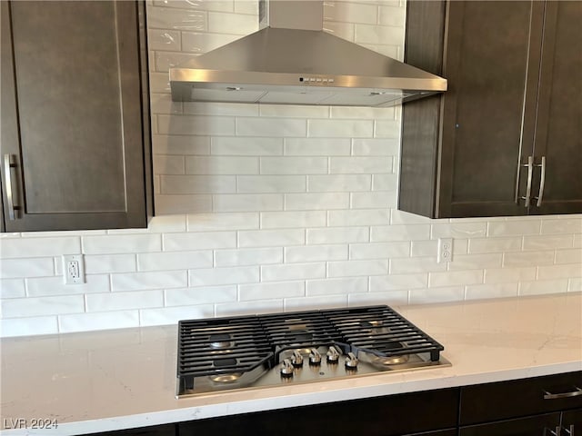 kitchen featuring tasteful backsplash, dark brown cabinets, wall chimney range hood, and stainless steel gas stovetop