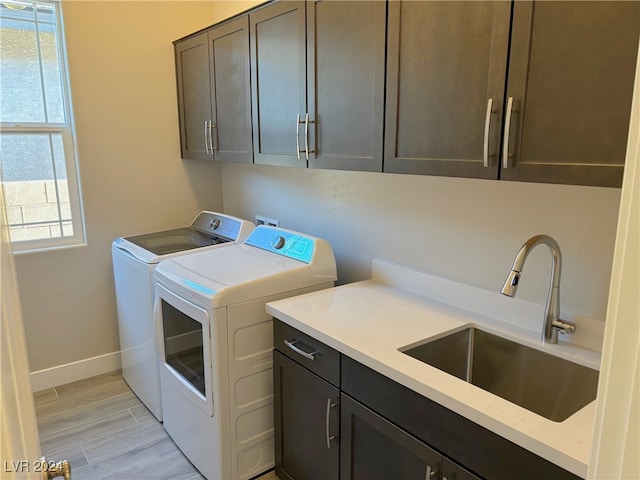 laundry room with washer and dryer, sink, cabinets, and light hardwood / wood-style flooring