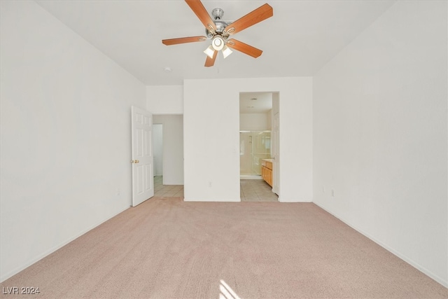 unfurnished bedroom featuring light carpet, connected bathroom, and ceiling fan