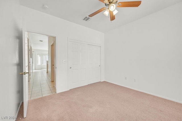 unfurnished bedroom with ceiling fan, light colored carpet, and a closet