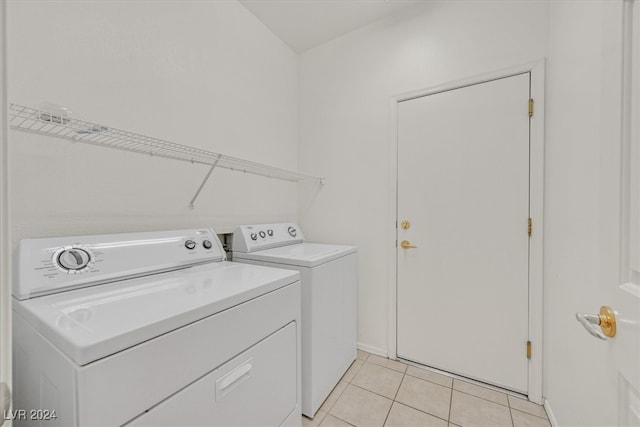 clothes washing area featuring light tile patterned flooring and washer and dryer