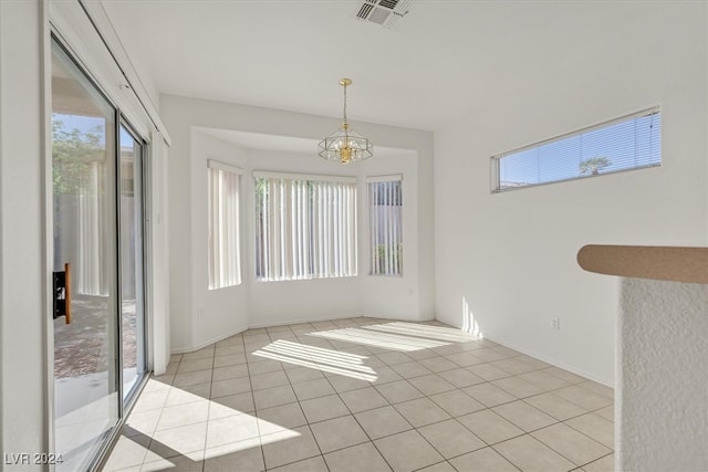 tiled empty room featuring a chandelier and a healthy amount of sunlight