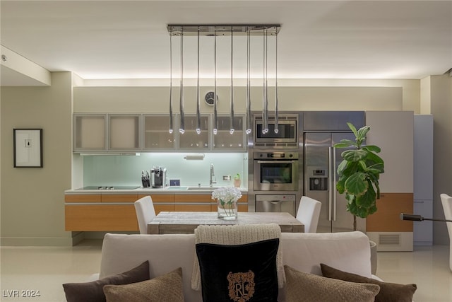 kitchen with appliances with stainless steel finishes, hanging light fixtures, and sink