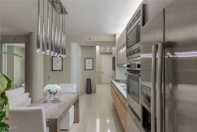 kitchen featuring stainless steel appliances, light tile patterned floors, and decorative light fixtures