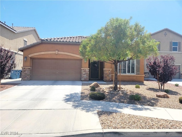 1152 Bear Head St, Henderson, NV 89011 - view of front of home featuring driveway, stone siding, stucco siding, an attached garage, and a tiled roof