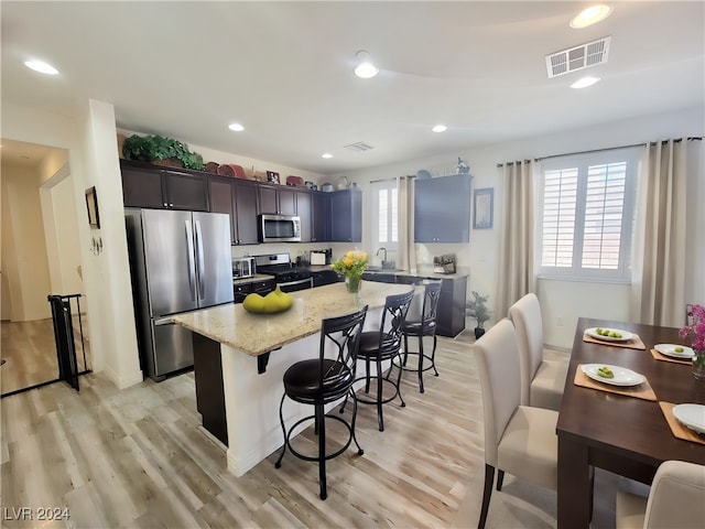 kitchen featuring stainless steel appliances, a center island, light wood-type flooring, and sink