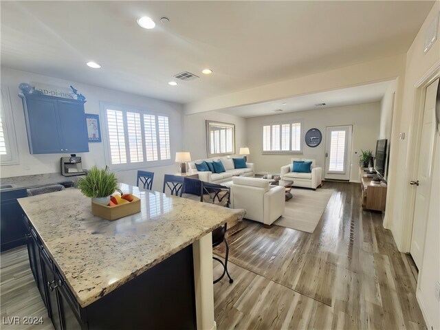 kitchen with light stone countertops, light hardwood / wood-style flooring, plenty of natural light, and a kitchen island