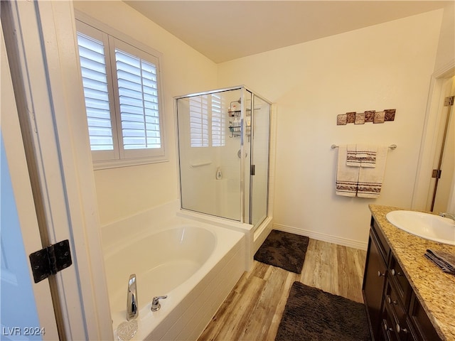 bathroom with plus walk in shower, hardwood / wood-style flooring, and vanity