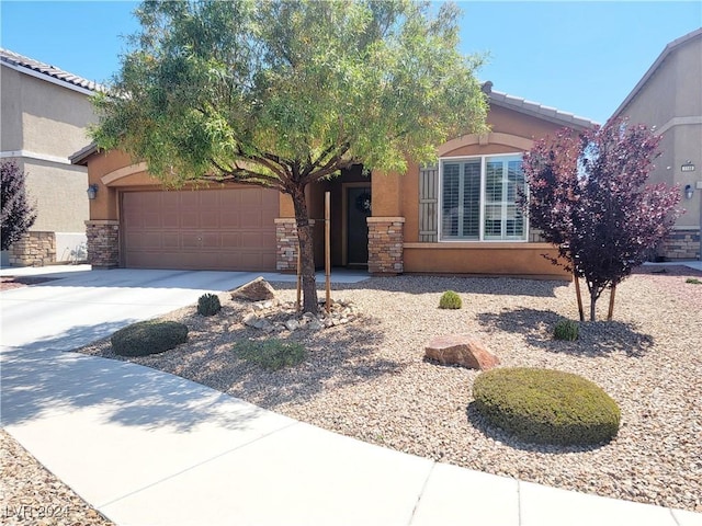 1152 Bear Head St, Henderson, NV 89011 - view of front of home featuring stone siding, an attached garage, concrete driveway, and stucco siding