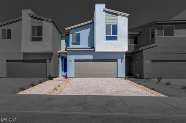 view of front of property with stucco siding, a garage, and decorative driveway