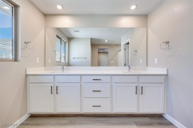 bathroom featuring double vanity, a sink, and baseboards