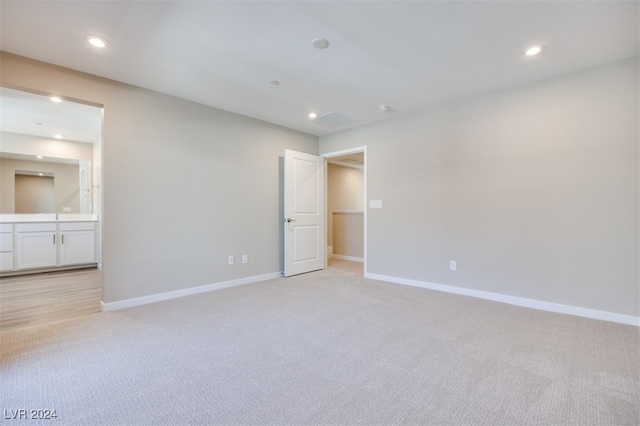 unfurnished bedroom featuring light carpet and ensuite bath