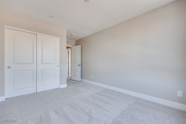 unfurnished bedroom with a closet and light colored carpet