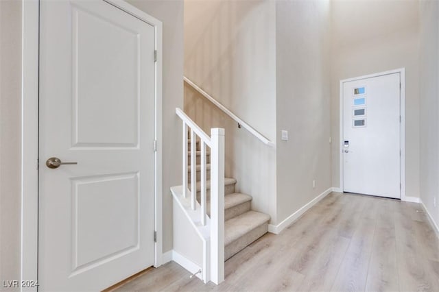 foyer featuring baseboards, stairs, and wood finished floors
