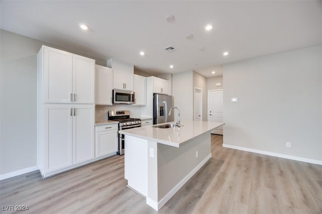kitchen featuring a kitchen island with sink, white cabinetry, light wood-style floors, and appliances with stainless steel finishes