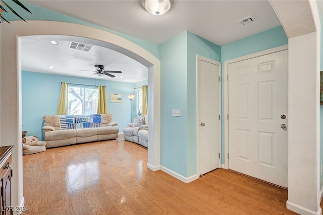 foyer entrance with ceiling fan and light wood-type flooring