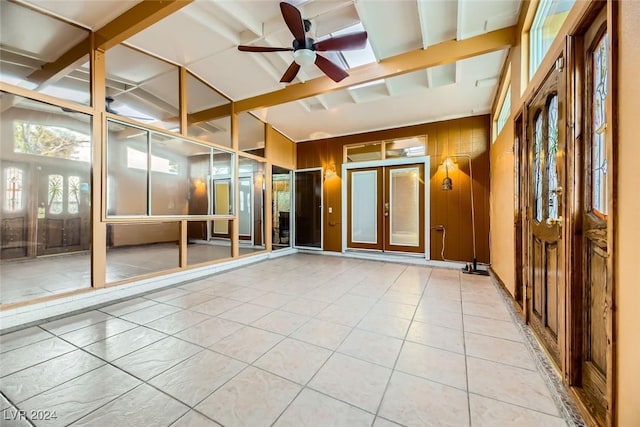 interior space featuring ceiling fan, wooden walls, and lofted ceiling with beams