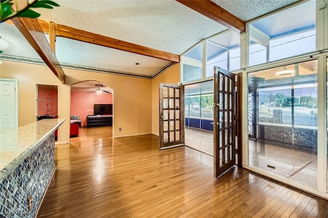 living room with vaulted ceiling with beams, wood-type flooring, a textured ceiling, and french doors