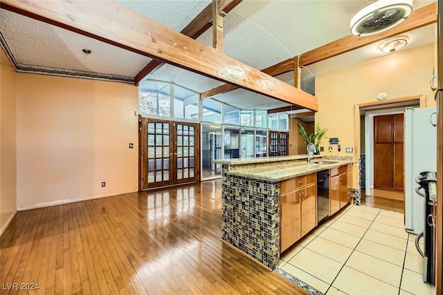 kitchen with french doors, dishwasher, lofted ceiling with beams, light hardwood / wood-style floors, and a textured ceiling