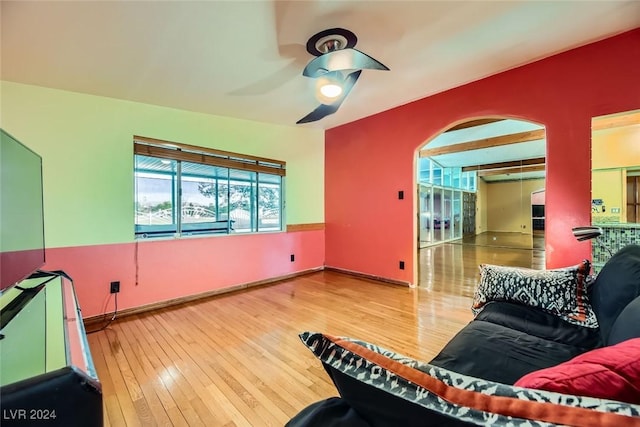 living room featuring beam ceiling, ceiling fan, and hardwood / wood-style floors