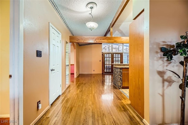 hall featuring french doors, a textured ceiling, hardwood / wood-style flooring, and ornamental molding