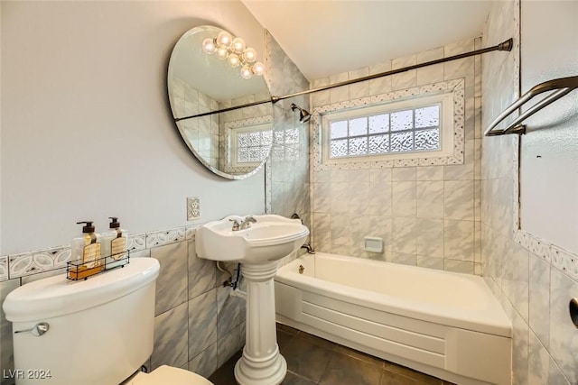 bathroom featuring tile patterned flooring, tiled shower / bath, toilet, and tile walls