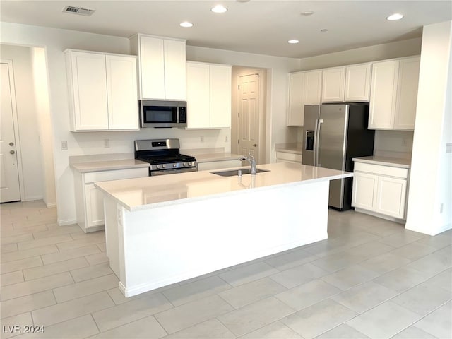 kitchen featuring sink, white cabinetry, stainless steel appliances, and an island with sink