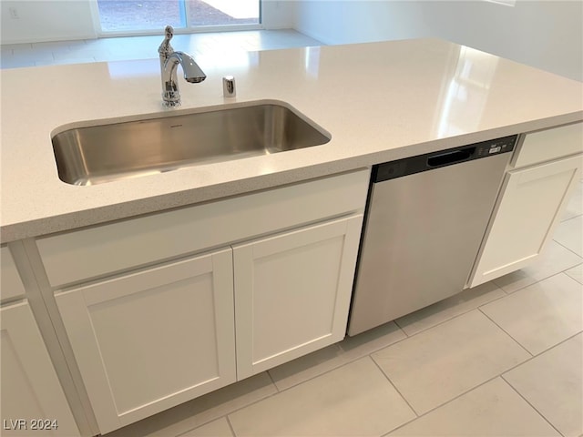 kitchen with white cabinetry, sink, light tile patterned floors, and stainless steel dishwasher