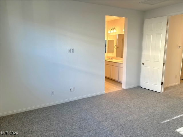 unfurnished bedroom featuring light colored carpet and ensuite bath