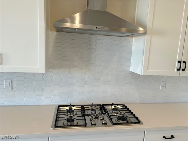 kitchen featuring decorative backsplash, gas stovetop, white cabinetry, and wall chimney exhaust hood