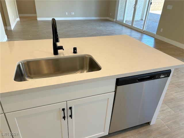 kitchen with dishwasher, white cabinets, sink, light stone countertops, and light hardwood / wood-style floors