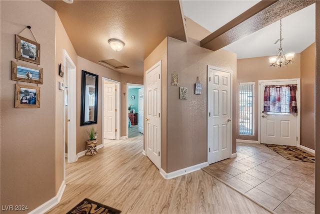 entryway with an inviting chandelier, light hardwood / wood-style flooring, and a textured ceiling