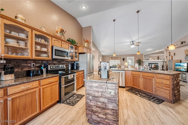 kitchen with lofted ceiling, appliances with stainless steel finishes, hanging light fixtures, and a kitchen island