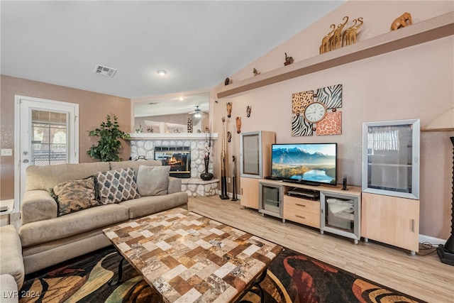 living room featuring a fireplace, vaulted ceiling, and light hardwood / wood-style flooring