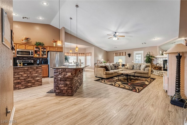 living room with ceiling fan, lofted ceiling, light hardwood / wood-style floors, and a healthy amount of sunlight