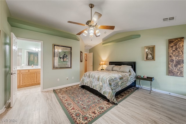 bedroom featuring light hardwood / wood-style floors, lofted ceiling, ensuite bath, and ceiling fan