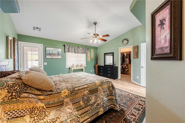 bedroom with ceiling fan, lofted ceiling, a walk in closet, a closet, and light wood-type flooring