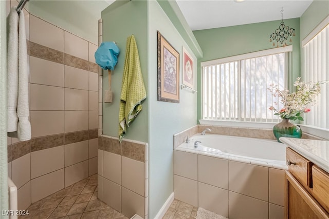 bathroom featuring vanity, a relaxing tiled tub, and tile patterned flooring