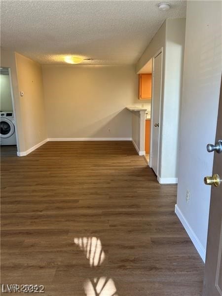 unfurnished living room featuring washer / clothes dryer, a textured ceiling, and dark hardwood / wood-style flooring