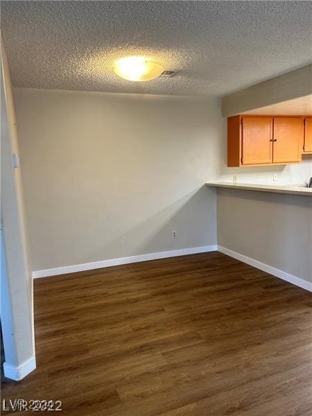 unfurnished dining area featuring a textured ceiling and dark hardwood / wood-style floors