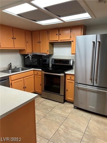 kitchen with appliances with stainless steel finishes, light tile patterned flooring, and sink