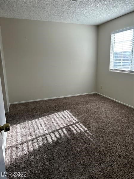 carpeted empty room featuring a textured ceiling