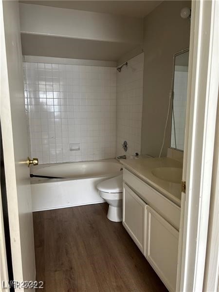 full bathroom featuring hardwood / wood-style floors, vanity, toilet, and tiled shower / bath combo