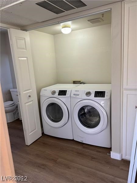 clothes washing area featuring dark wood-type flooring and washer and dryer