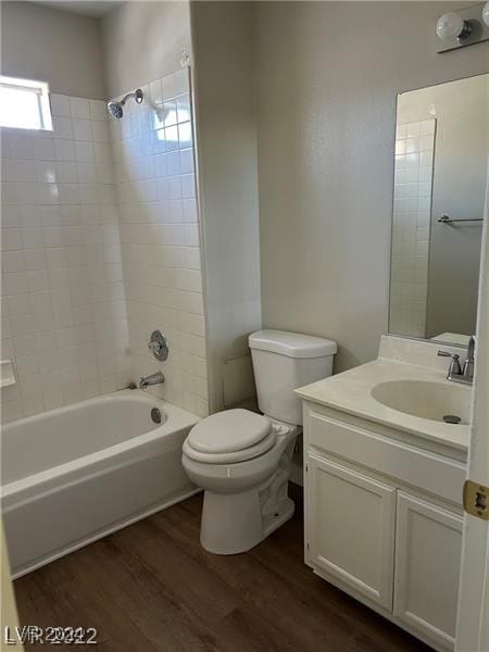 full bathroom with hardwood / wood-style flooring, tiled shower / bath combo, vanity, and toilet