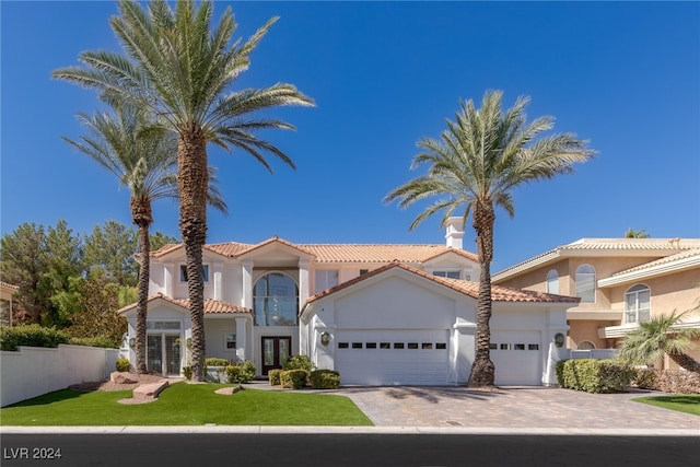 mediterranean / spanish house featuring a garage and a front lawn