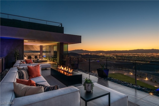 patio terrace at dusk featuring a balcony, outdoor lounge area, and a mountain view